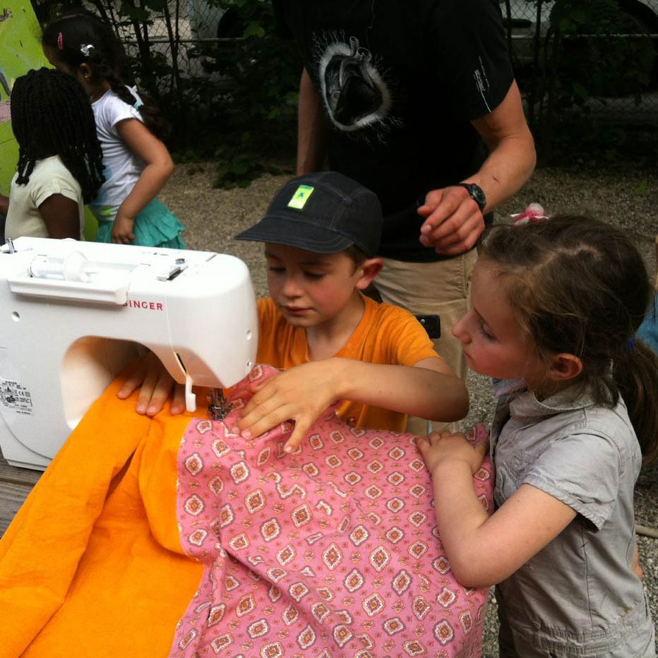 des enfants apprennent à utiliser une machine à coudre